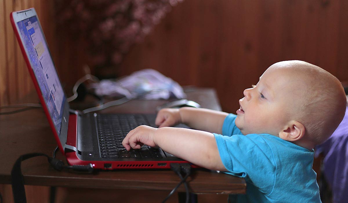 small child in front of computer, with hands on keyboard