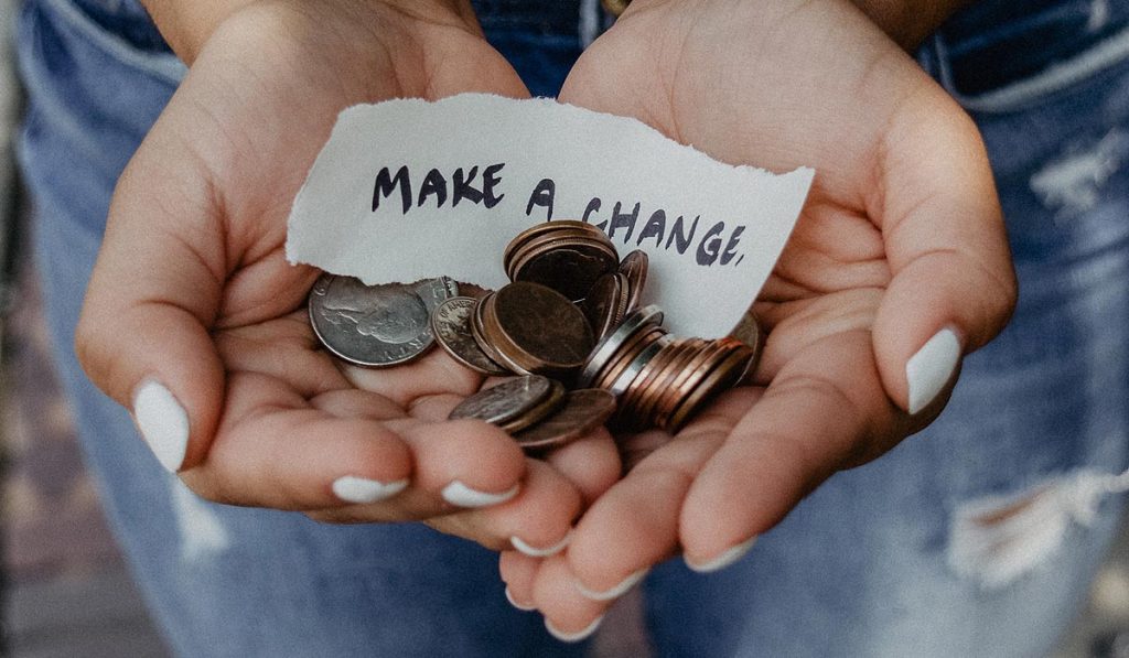 hands holding a bunch of coins and paper with words "Make a change"