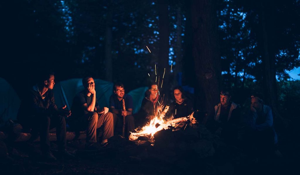 Men and women sharing stories around a campfire
