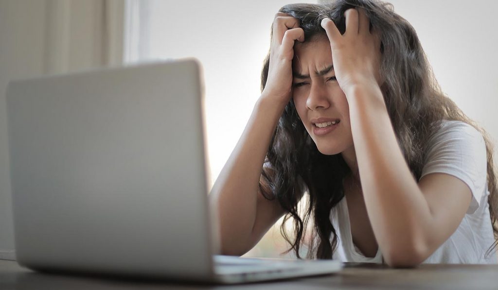 Frustrated woman in front of computer, tearing her hair