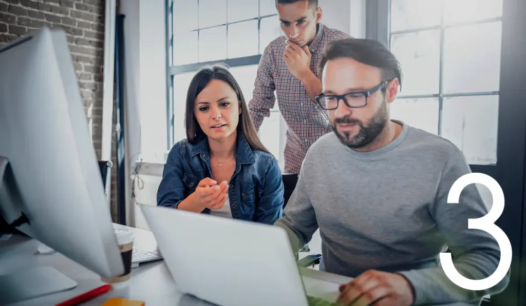 3 people in front of computer, discussing content