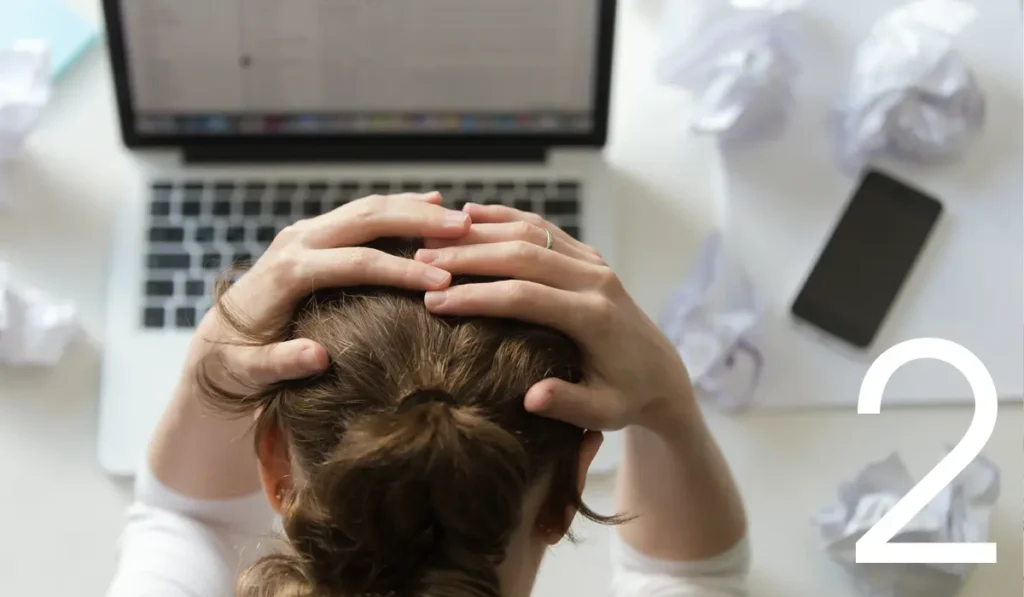 woman in front of computer, with hands on her head in frustration